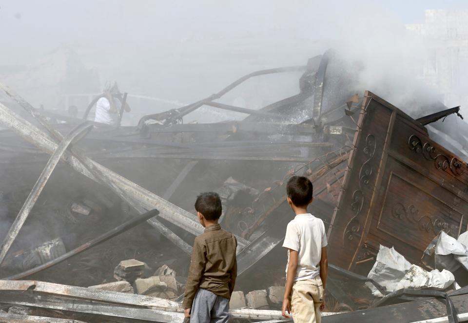 Boys look as a worker uses a hose to put down fire at a a vehicle oil and tires store hit by Saudi-led air strikes in Sanaa, Yemen July 2, 2020.