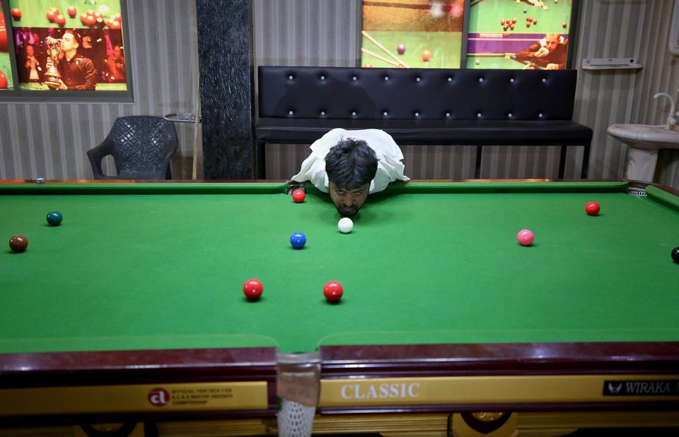 Mohammad Ikram plays snooker with his chin at a local snooker club in Samundri town, Pakistan, October 25, 2020.
