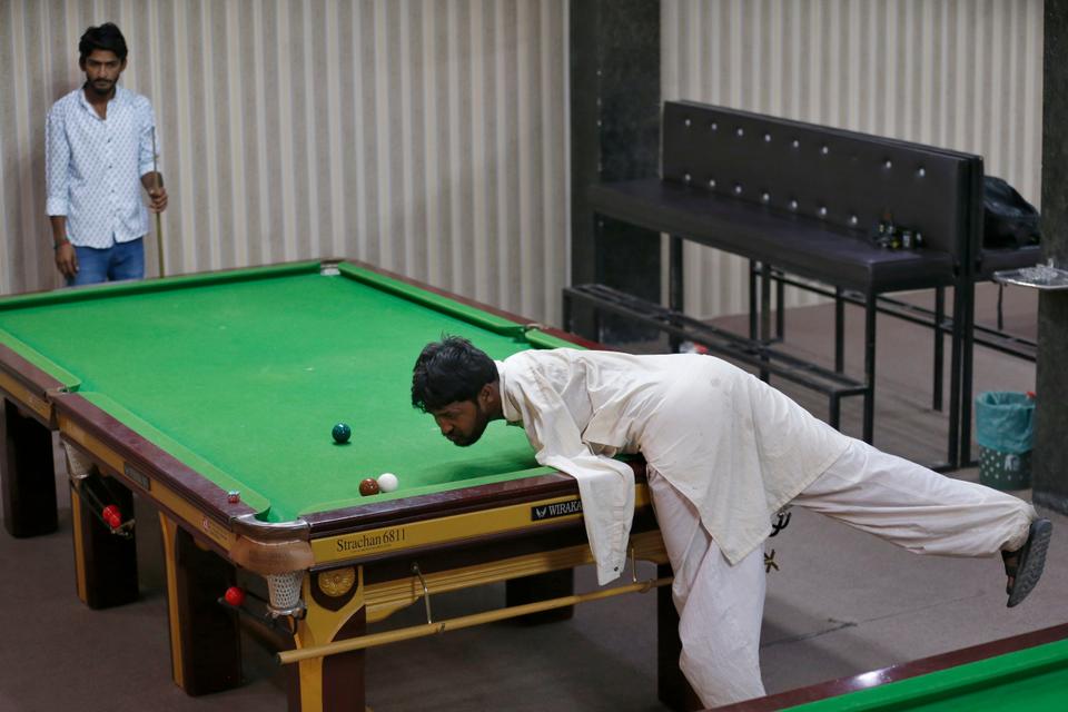 Mohammad Ikram plays snooker with his chin at a local snooker club in Samundri town, Pakistan, October 25, 2020.