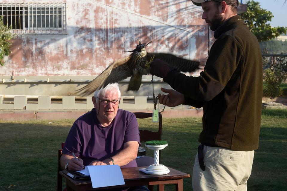 In this picture taken on November 23, 2020, Bob Dalton (L), a veteran falcon conservationist and project co-ordinator for Project Lugger, and Hielko Van Rijthoven, a conservationist working with Wings of Change, weigh a falcon as they work on the rehabilitation of falcons seized by Pakistani authorities from smugglers, in the port city of Karachi.