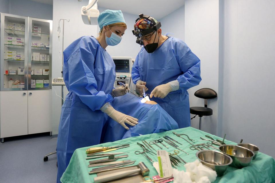 Luis Medical Centre director, surgeon Kostandin Balloma (R) conducts a plastic surgery intervention at the nose of a woman at his clinic in Tirana on February 19, 2021